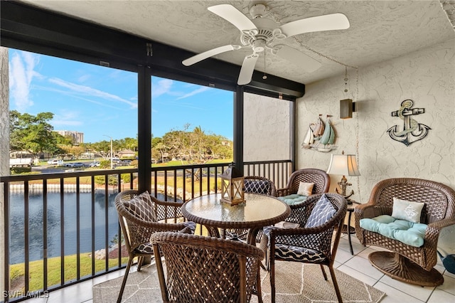 sunroom featuring a water view and ceiling fan