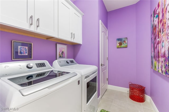 clothes washing area with light tile patterned floors, washing machine and dryer, cabinet space, and baseboards