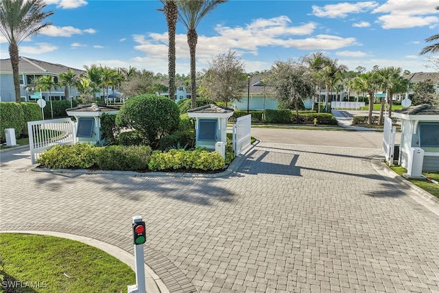 view of street featuring curbs, a gated entry, and a residential view