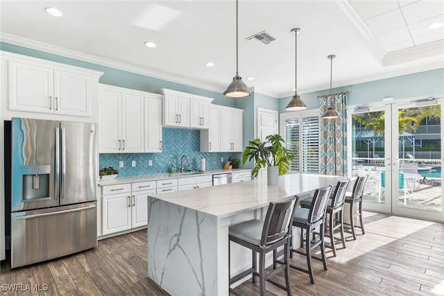 kitchen featuring a center island, visible vents, white cabinetry, appliances with stainless steel finishes, and light stone countertops