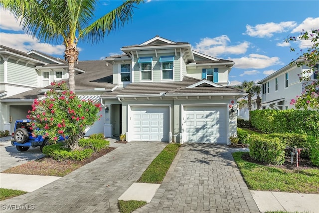 view of front of property featuring an attached garage, a tile roof, and decorative driveway