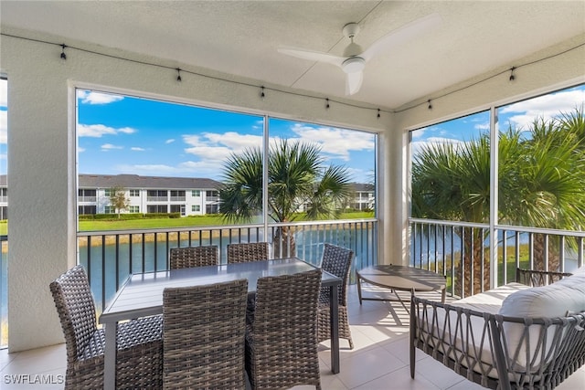 sunroom / solarium featuring a water view and a ceiling fan