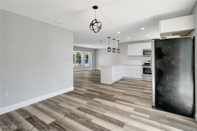 kitchen with light countertops, hanging light fixtures, appliances with stainless steel finishes, open floor plan, and white cabinets