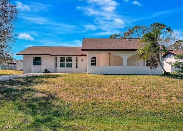 ranch-style house featuring a front yard, fence, and stucco siding