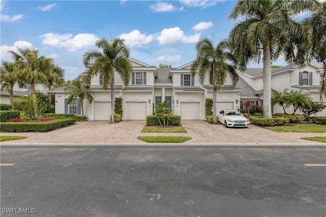 townhome / multi-family property featuring driveway, an attached garage, and stucco siding