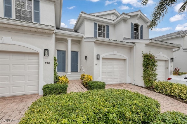 view of front of property with an attached garage, decorative driveway, and stucco siding