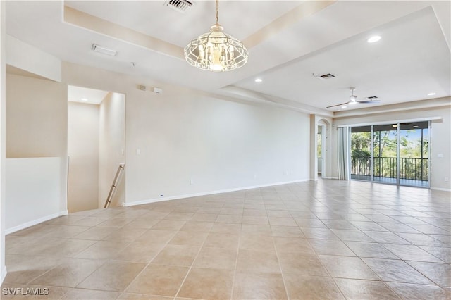 empty room featuring a tray ceiling, light tile patterned floors, visible vents, baseboards, and ceiling fan with notable chandelier