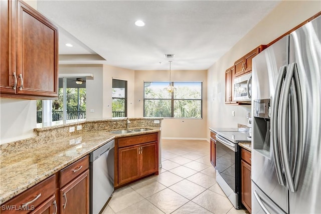 kitchen with stainless steel appliances, a peninsula, a sink, light stone countertops, and pendant lighting