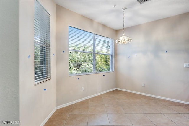 empty room with a chandelier, light tile patterned flooring, and baseboards