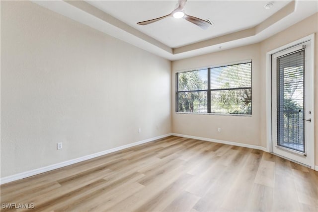 empty room with light wood-type flooring, a ceiling fan, and baseboards