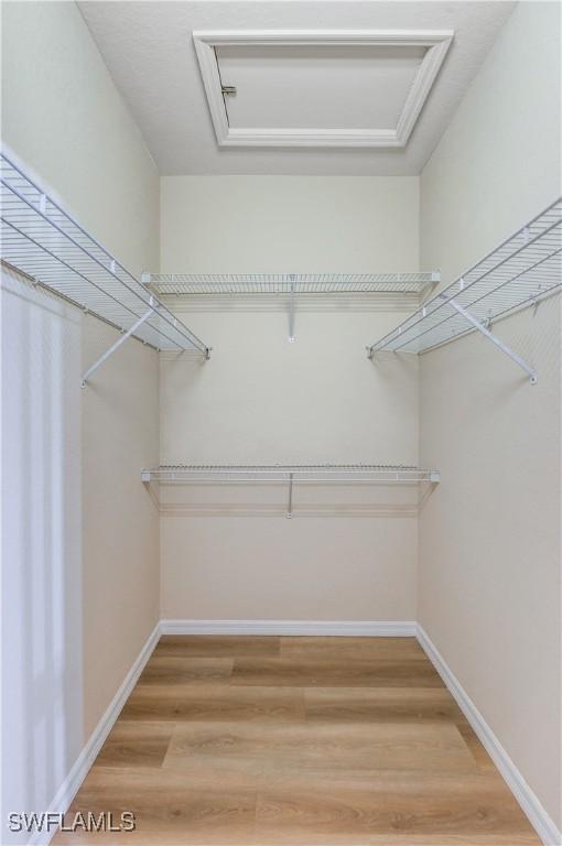 spacious closet featuring attic access and wood finished floors