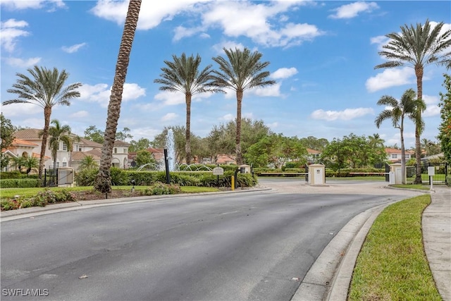 view of street with a gate, a residential view, a gated entry, and curbs