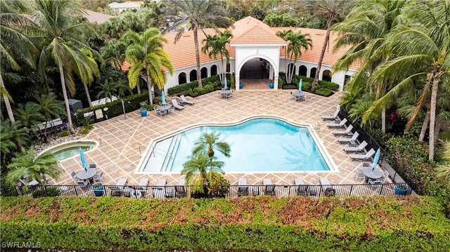 view of pool with a patio, fence, and a hot tub