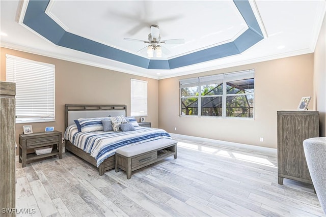 bedroom with a ceiling fan, crown molding, a tray ceiling, and wood finished floors