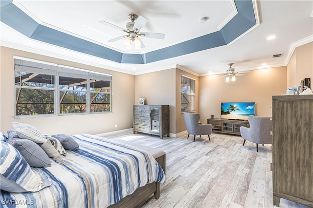 bedroom featuring light wood finished floors, visible vents, baseboards, ornamental molding, and a tray ceiling