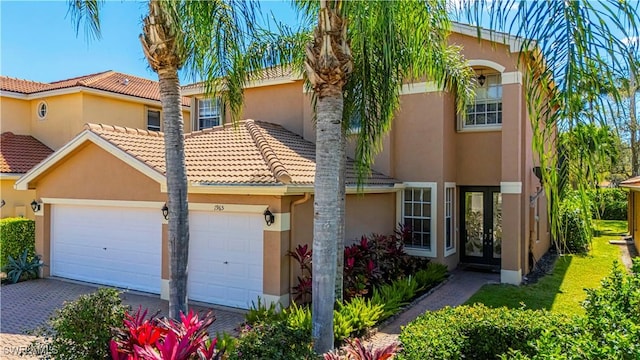 view of front of property with an attached garage, stucco siding, decorative driveway, and french doors