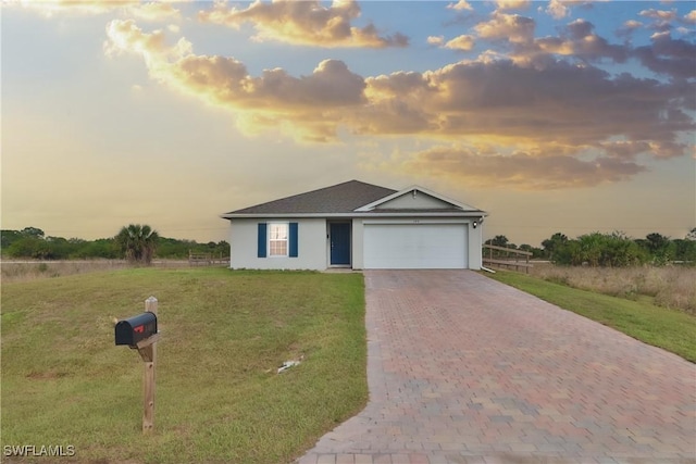 ranch-style home featuring an attached garage, decorative driveway, and a front yard