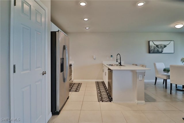 kitchen with light countertops, appliances with stainless steel finishes, light tile patterned flooring, a sink, and a peninsula