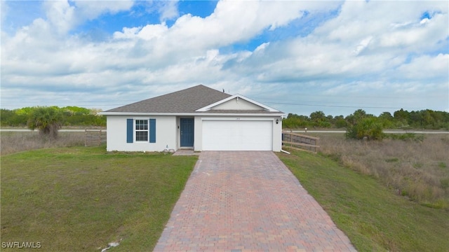 ranch-style house featuring an attached garage, decorative driveway, a front yard, and fence