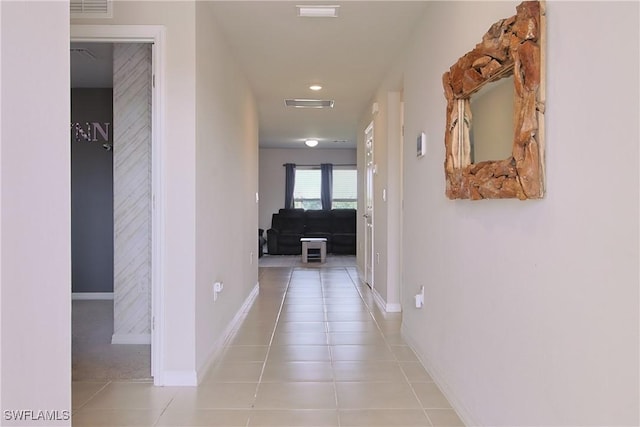 hall featuring visible vents, baseboards, and light tile patterned floors