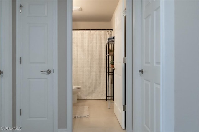 full bathroom featuring toilet, curtained shower, tile patterned flooring, and a closet