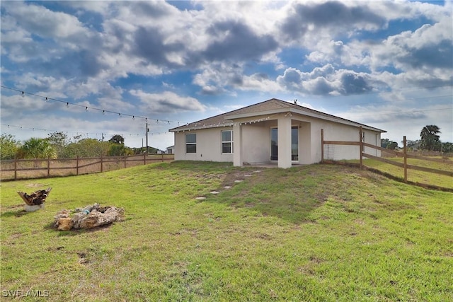 back of property with stucco siding, a fenced backyard, and a yard