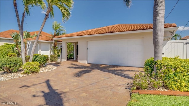 mediterranean / spanish-style house featuring a tiled roof, an attached garage, and stucco siding