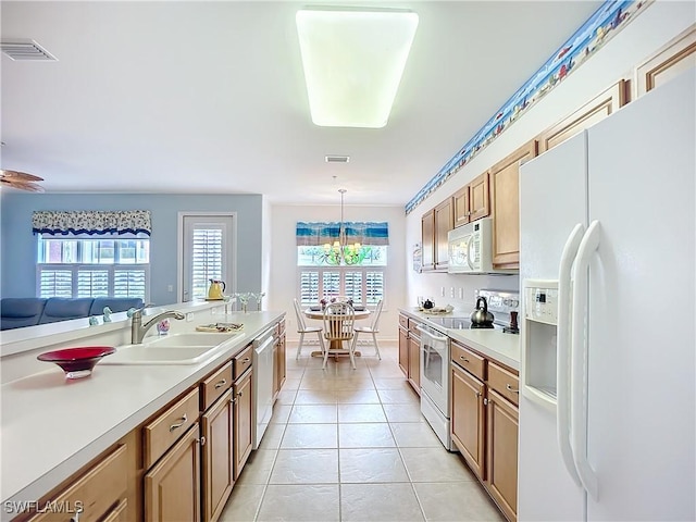 kitchen with white appliances, a sink, visible vents, light countertops, and hanging light fixtures