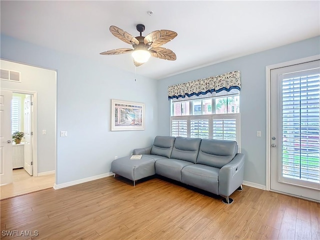 living room with ceiling fan, light wood-style flooring, visible vents, and baseboards