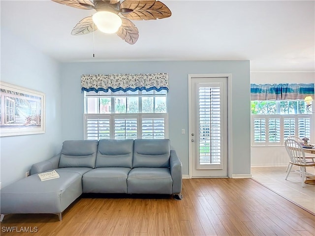 living room featuring light wood-style floors, a wealth of natural light, baseboards, and a ceiling fan