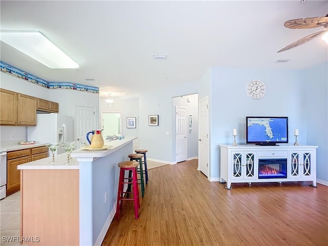 kitchen featuring open floor plan, light countertops, white fridge with ice dispenser, a kitchen bar, and a center island with sink