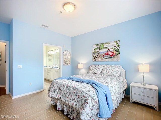 bedroom with light wood-type flooring, visible vents, baseboards, and ensuite bathroom