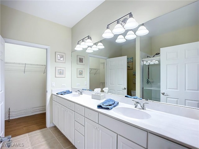 full bath with double vanity, an enclosed shower, a sink, and tile patterned floors