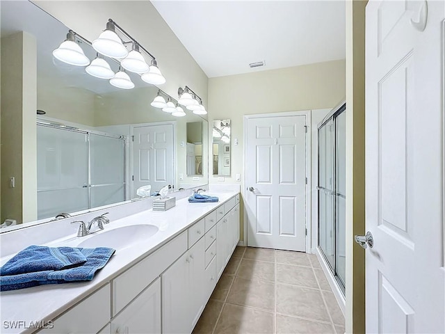 bathroom featuring double vanity, a stall shower, visible vents, tile patterned flooring, and a sink