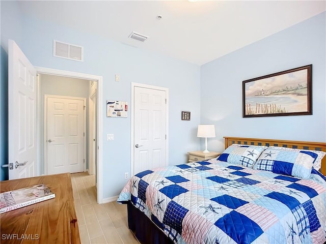 bedroom featuring light wood-type flooring, visible vents, and baseboards