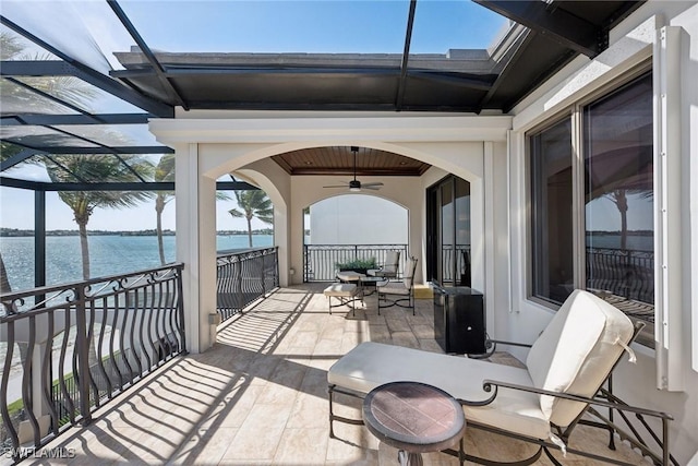 view of patio with a water view, a balcony, and a ceiling fan