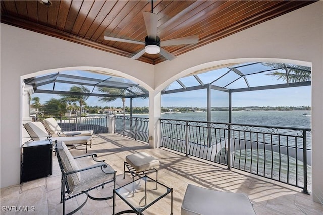 view of patio featuring a water view, ceiling fan, and a lanai