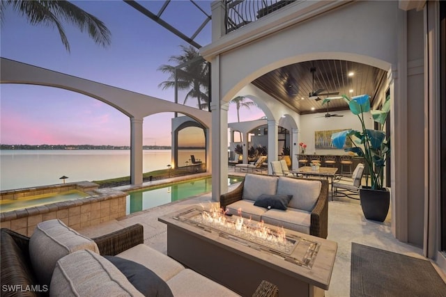 view of patio featuring a water view, an outdoor living space with a fire pit, a balcony, and an outdoor pool