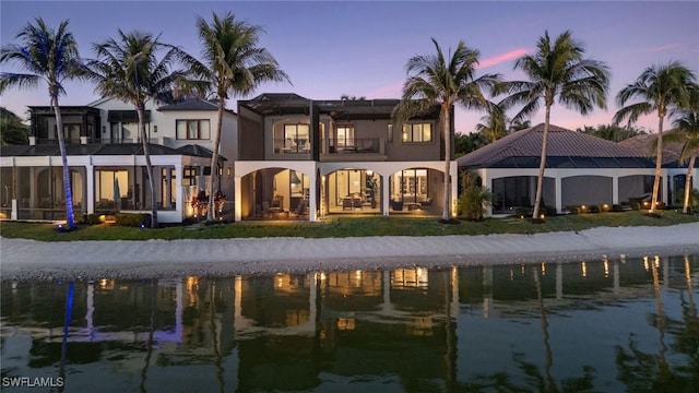 rear view of property with a water view, a balcony, and stucco siding