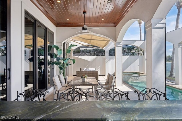 view of patio / terrace with ceiling fan, a water view, fence, a fenced in pool, and outdoor dining space