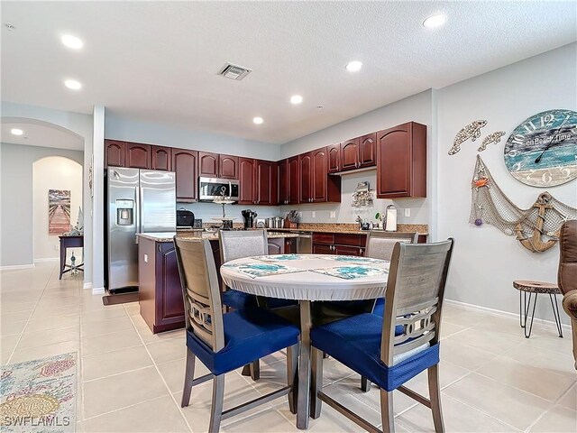 kitchen featuring light tile patterned floors, visible vents, baseboards, arched walkways, and appliances with stainless steel finishes