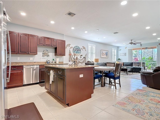 kitchen with stainless steel dishwasher, open floor plan, light tile patterned flooring, and visible vents