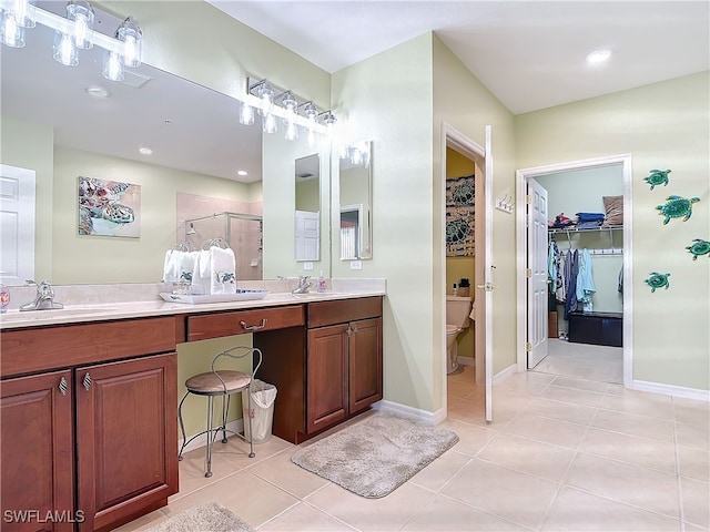 full bathroom with double vanity, a sink, tile patterned flooring, a shower stall, and a walk in closet