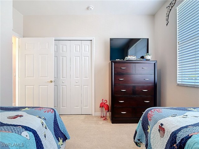 bedroom with light carpet and a closet