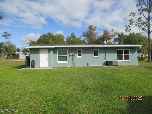 rear view of property with central air condition unit, a yard, and stucco siding