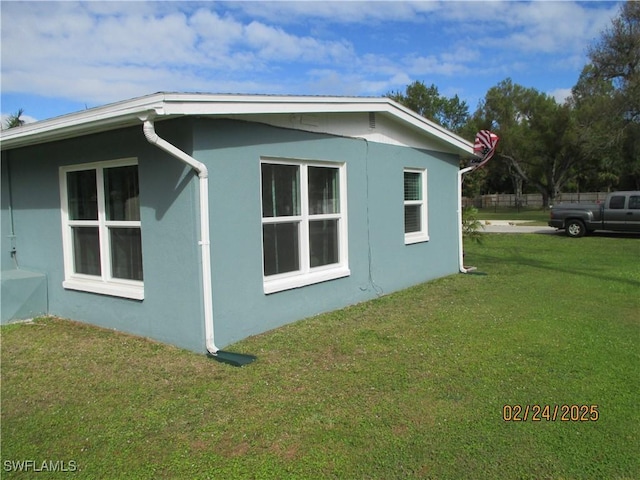 view of side of property featuring a lawn and stucco siding