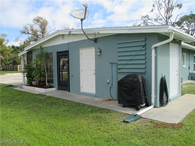 rear view of house with a lawn and stucco siding