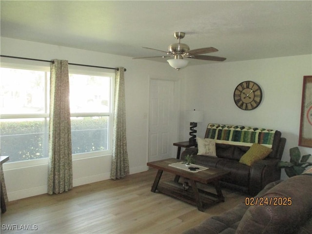 living area featuring a ceiling fan, baseboards, and wood finished floors