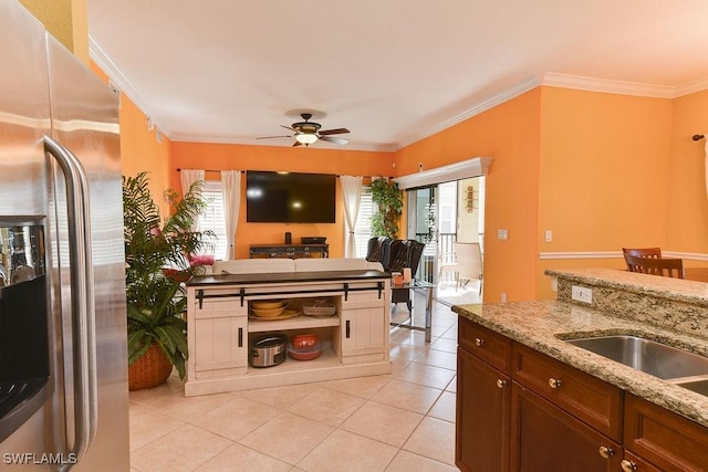 kitchen featuring ceiling fan, light tile patterned flooring, stainless steel fridge with ice dispenser, ornamental molding, and light stone countertops