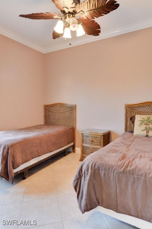 tiled bedroom with a ceiling fan and crown molding